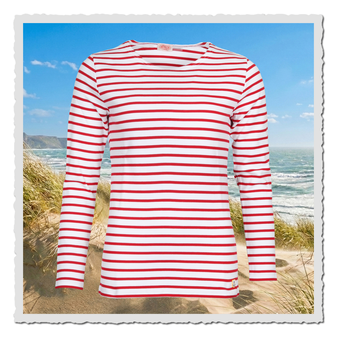 Weiß-rotes Damen-Ringelshirt von Armor Lux, Matrosinnen-Stil, vor Dünen und Meer als sommerliche Küstenkulisse präsentiert.